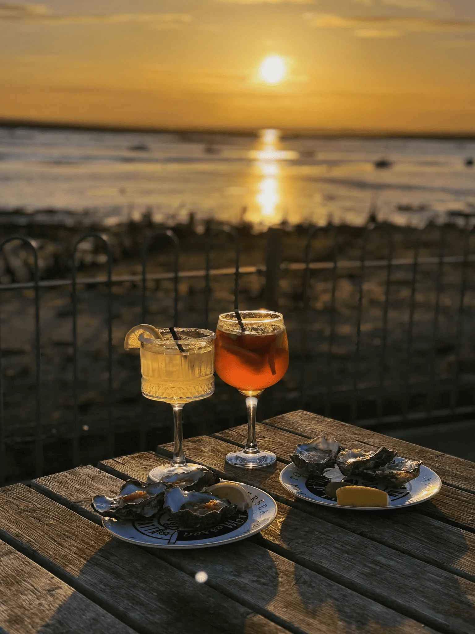 Two cocktails and plates of oysters overlooking the Blackwater at sunset