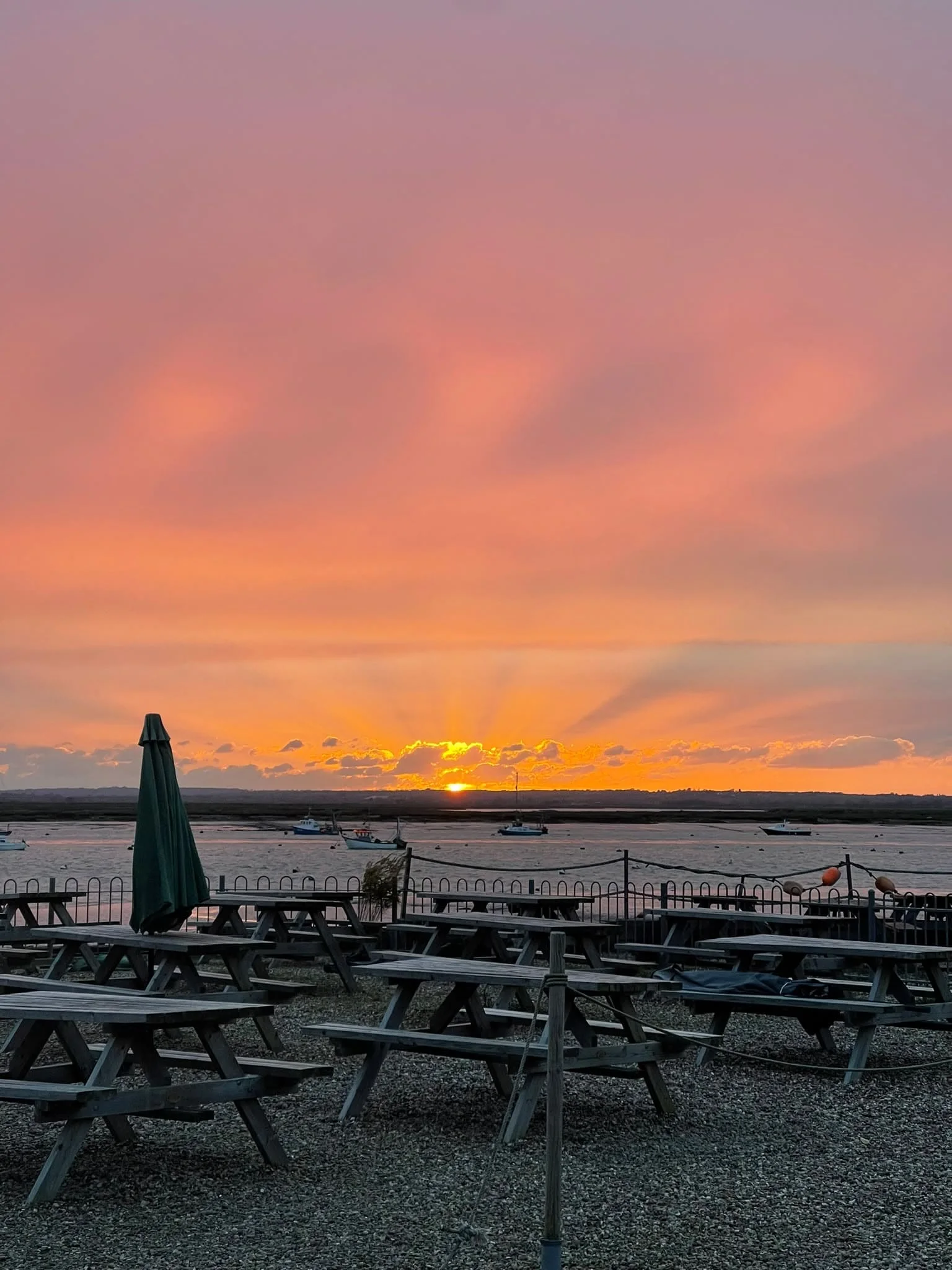 A vivid sunset beyond the waterside picnic tables at Seafood at Dawn